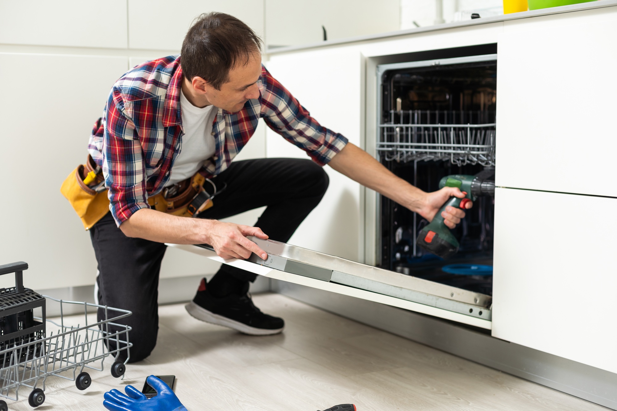Professional worker repairing the dishwasher in the kitchen